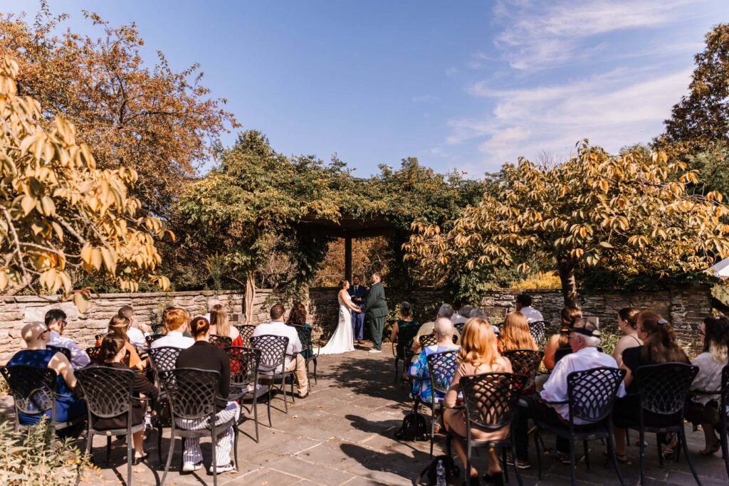 Couple marrying under a natural arbor at a public gardens.