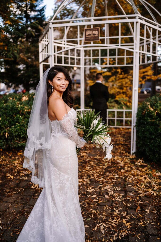 Bride about to surprise Groom for a first look under a white gazebo. 