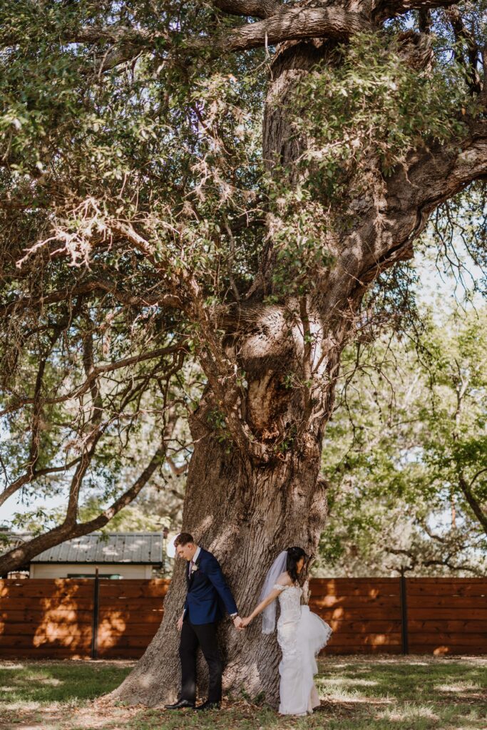 Bride and Groom share a first touch under a large old tree.