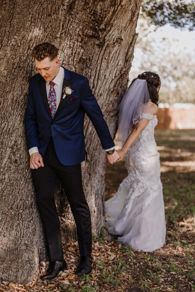 Bride and Groom share a first touch under a large old tree.