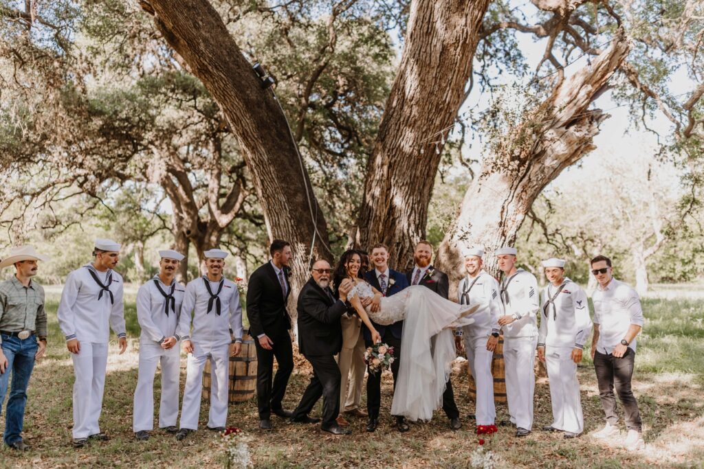The bridal party poses under a large old tree.