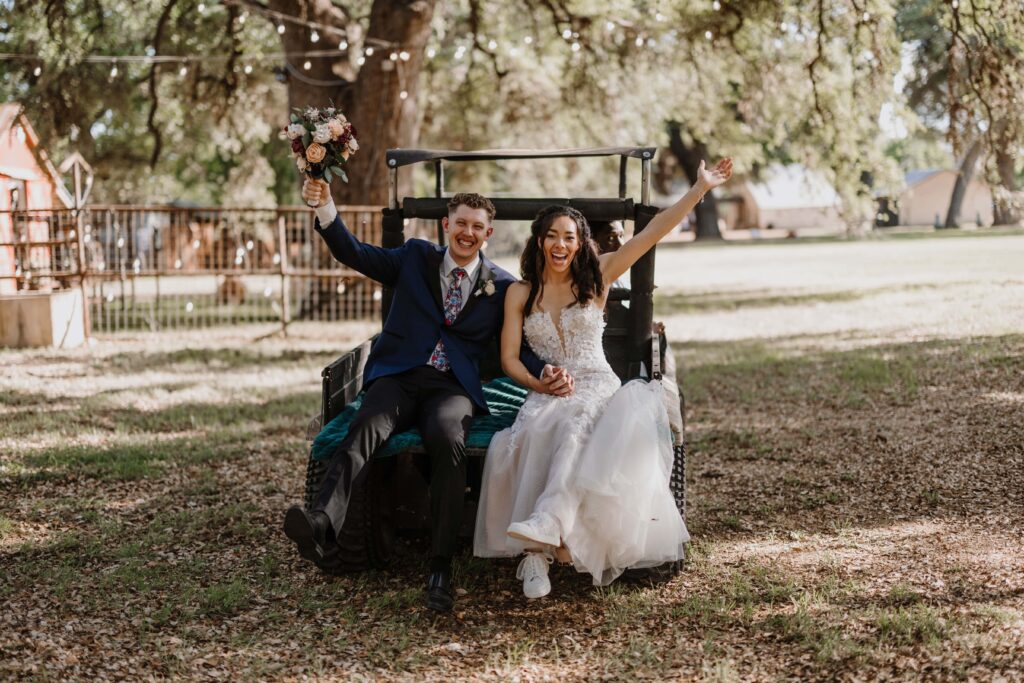 Bride and groom ride off into the sunset on a gold cart.