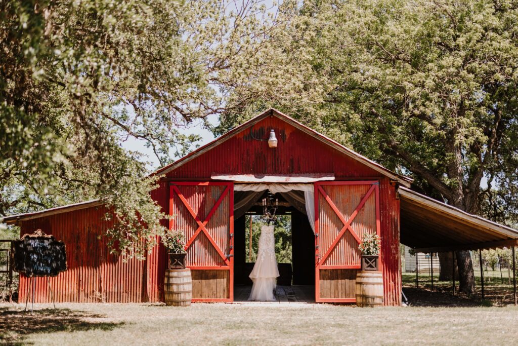 Wedding dress hanging from the doorway into a large old barn.