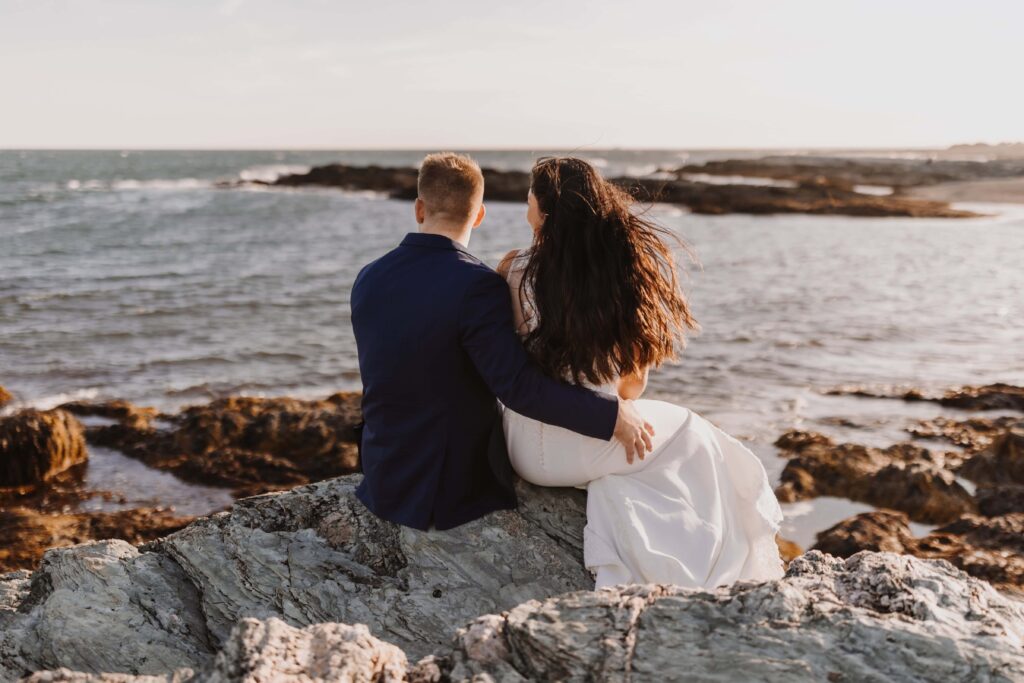 Newlywed couple looking out over the Rhode Island coast.