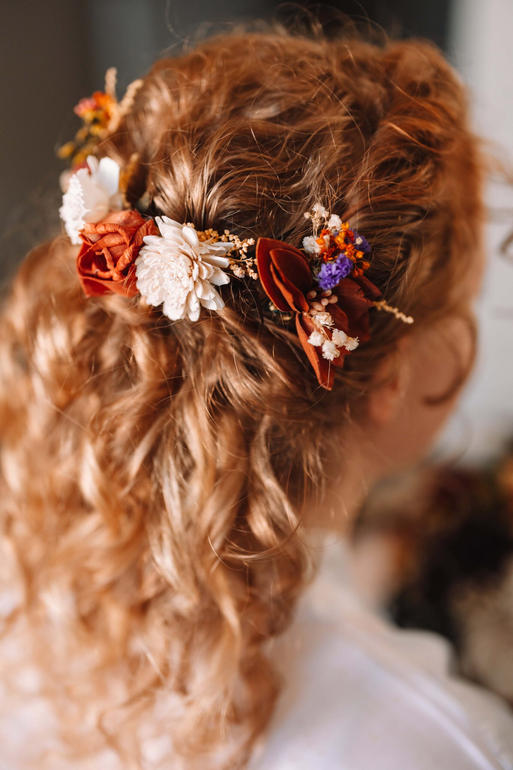Bride with blonde curly hair with floral pins woven in.