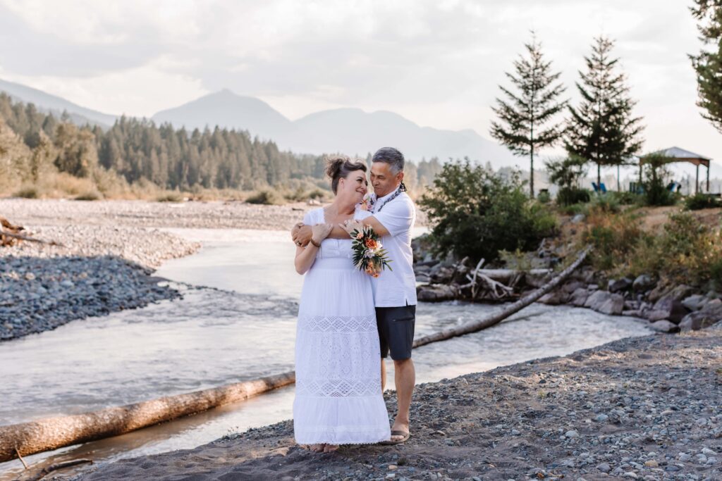Newlyweds embrace beside the reflection lakes at Mount Rainier National Park. 