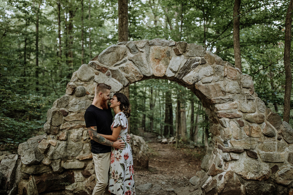 Newlyweds embrace under an old stone arch.