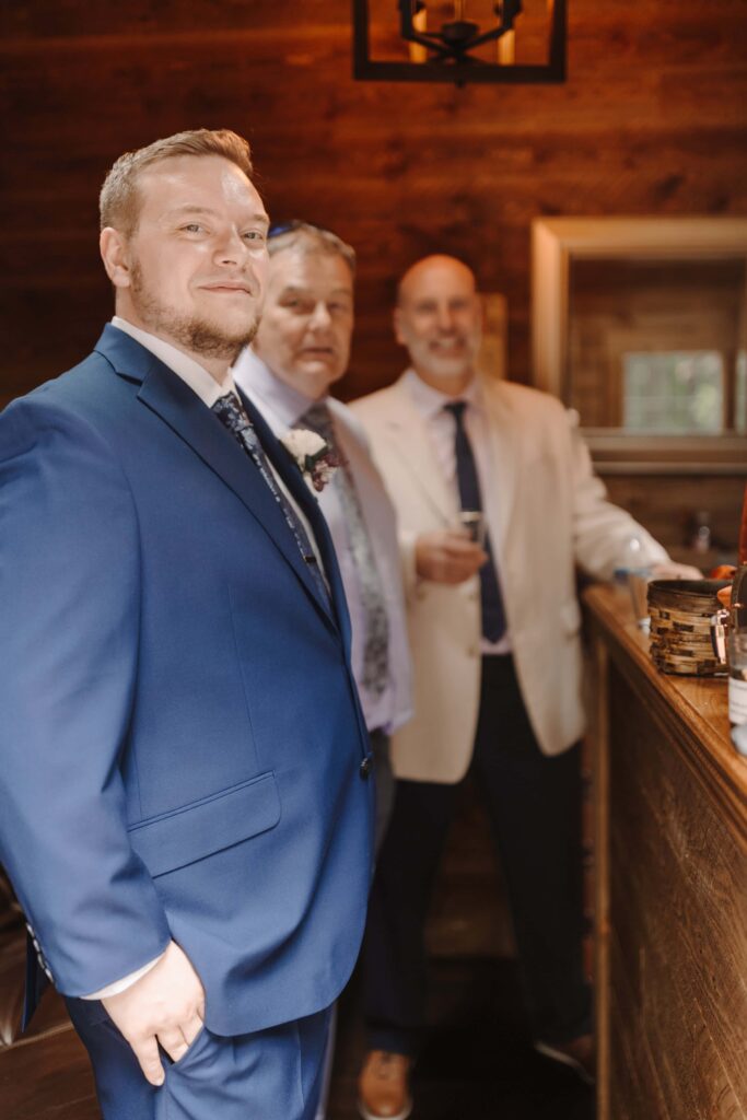 Fathers and brother have a moment of community before the micro wedding in the woods.