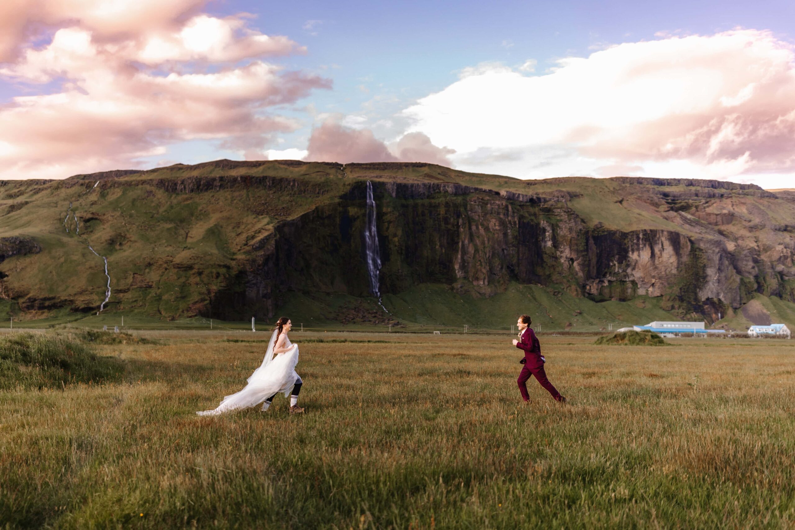 Bride and groom racing to meet each other in a field.