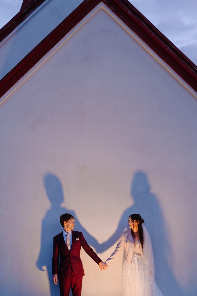 Bride and Groom in the shadow of a chapel.