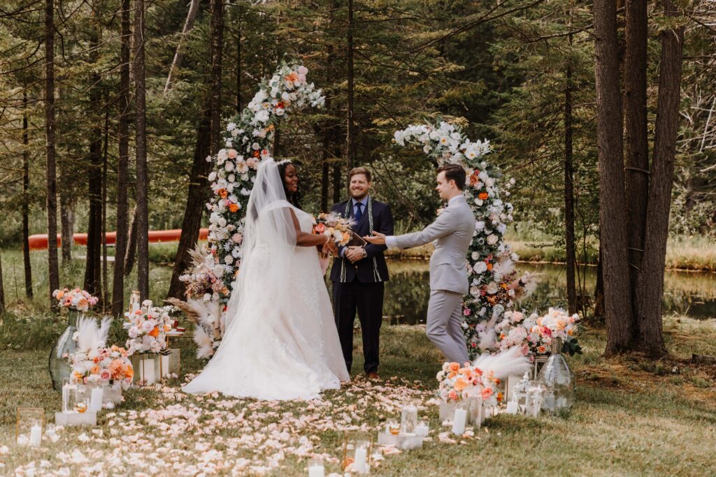 Summer Wedding ceremony amidst the outdoors surrounded by flowers.