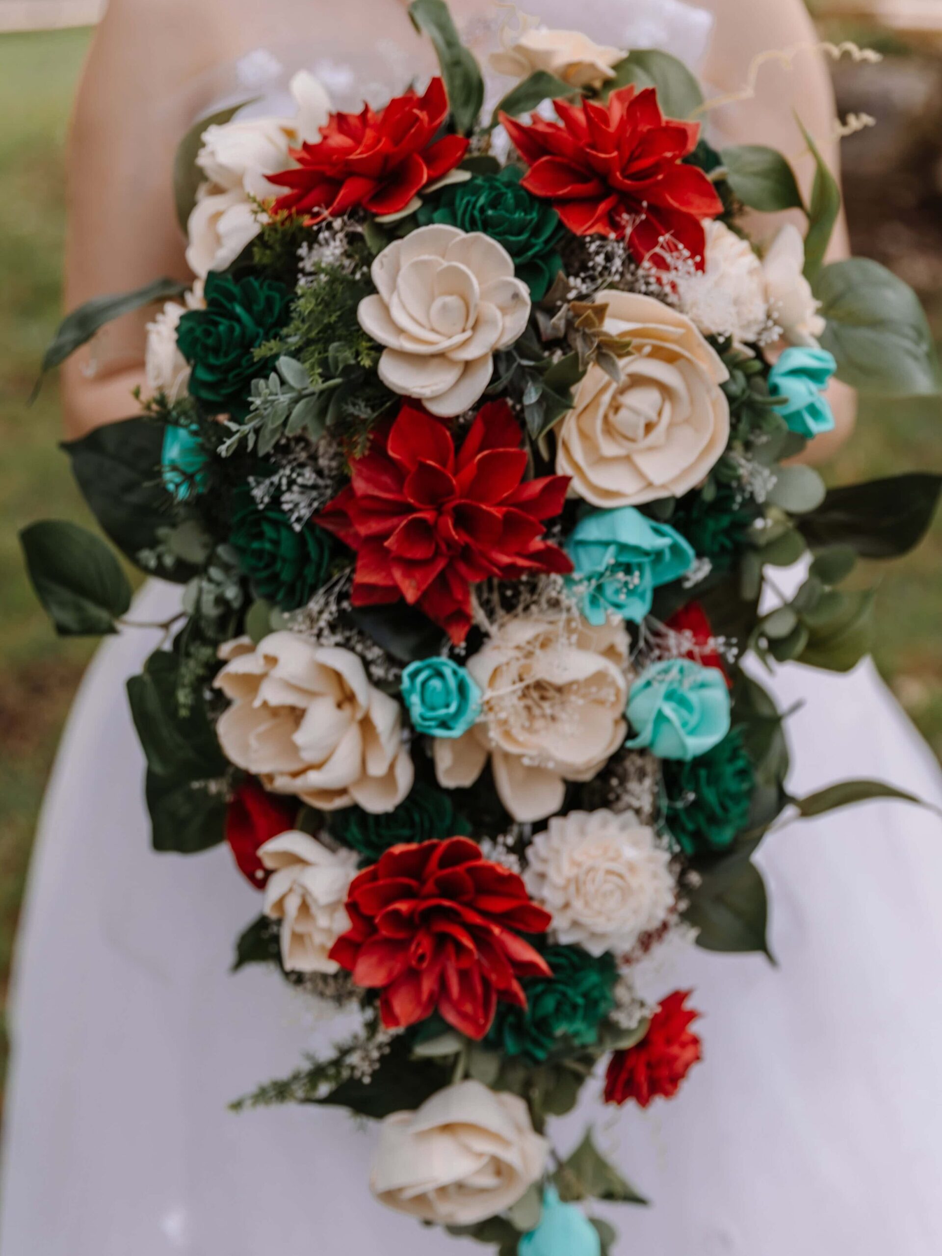 Photograph of a very large cascade bouquet made of burgundy, sage, and teal Sola flowers.