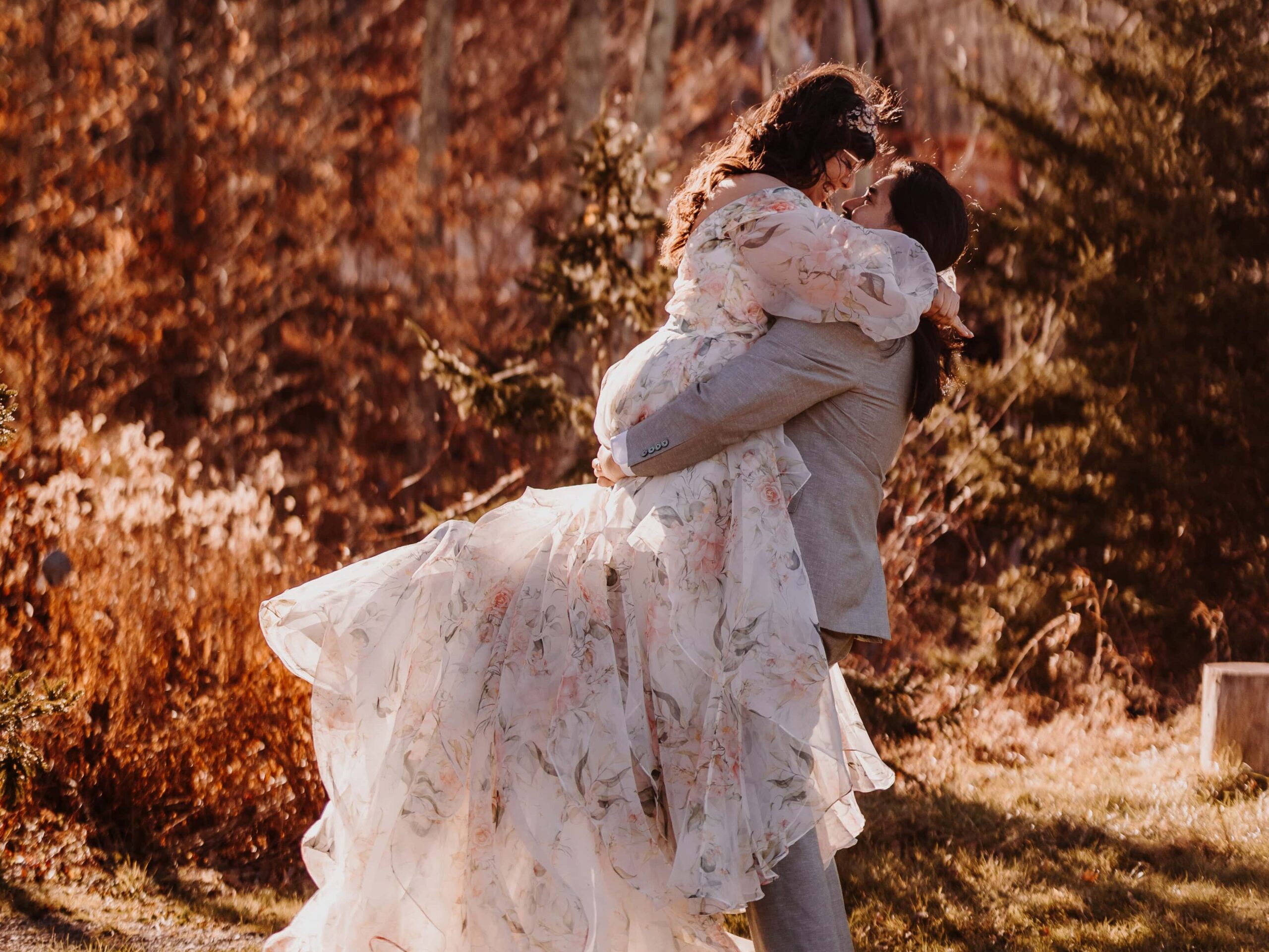 A Bride in a Bohemian style floral dress and her groom embrace.