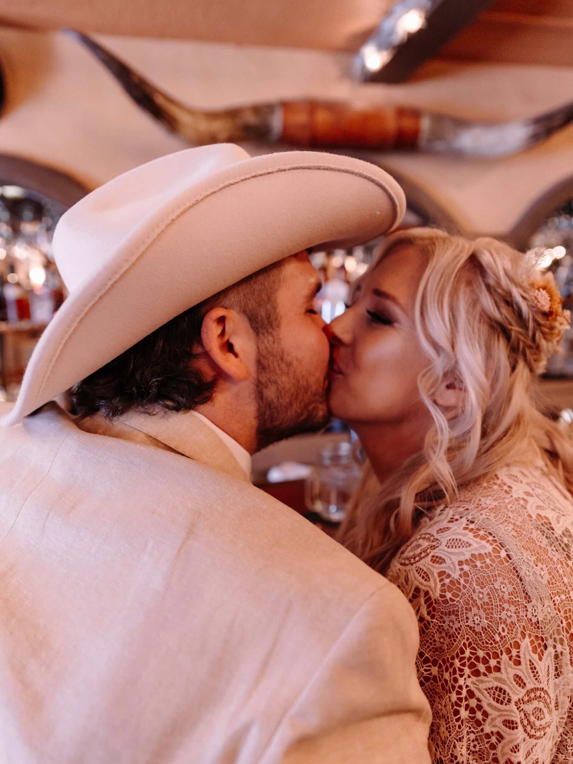 A photograph of a bride and groom in country attire kissing.