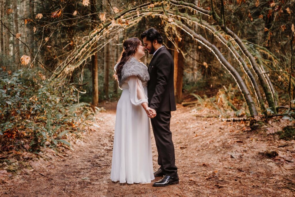 Bride and Groom Hold hands beneath a natural arch in golden hour light. 