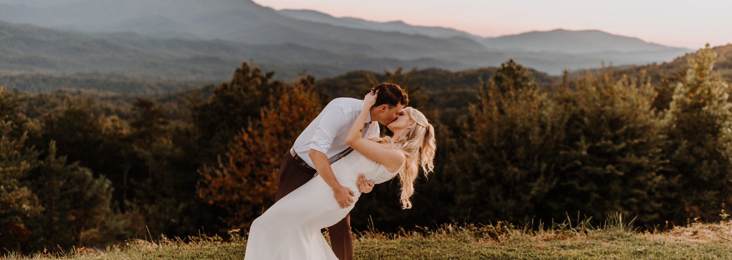Couple sharing a newlywed kiss atop a mountain vista in Tennessee.