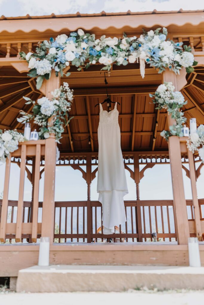 The bride's wedding gown hangs in the Tennessee breeze under their custom Sola wedding arch by Picked MD.