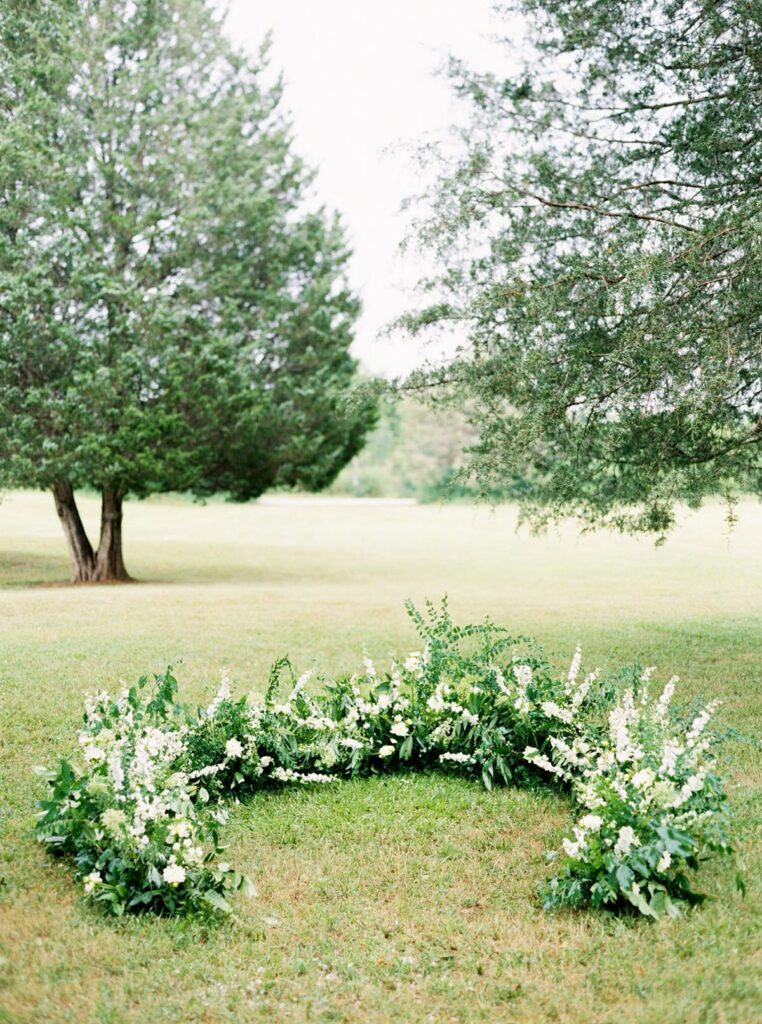 One great way to make your floral budget stretch: a ground arch for your ceremony that can be split into sections for reception centerpieces later.